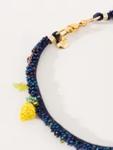 Collar corto con cordón azul bordado con mostacillas de vidrio y dijes de limones amarillos y hojas verdes bordados a mano con mostacillas.