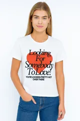 Remera blanca de algodón con estampado frontal de un corazón rojo y texto en negro.