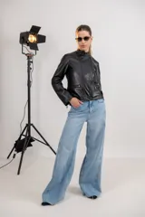 Chaqueta de cuero ovino color negro, con cuello mao, cierre asimétrico con cremallera, bolsillos laterales con cremallera y detalle de pespuntes en los hombros.