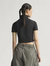 Crop top negro de Adidas con cuello alto, mangas cortas y aberturas frontales con lazos. Presenta las tres líneas características de la marca en color blanco en el cuello y el logo en el pecho.