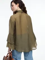 Camisa negra de lyocell y poliamida, con cuello clásico, mangas largas acampanadas con volados y cierre frontal con botones.