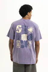 Remera color beige de corte holgado con estampado pequeño de palmera y la letra S en el centro del pecho.