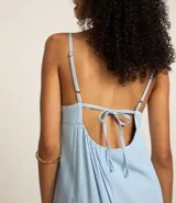 Vestido largo celeste de jeans con breteles finos, escote cuadrado, lazo en la espalda y abertura en la parte inferior.