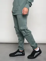 Pantalón de jogging gris con bolsillos cargo laterales y logo de la marca bordado en la pierna.