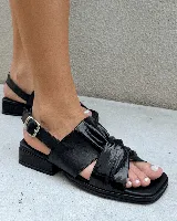 Sandalia negra de cuero con puntera cuadrada, tira ancha con nudo fruncido y tira fina ajustable en el talón. Posee un taco bajo y grueso.
