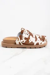 Zuecos con capellada de cuero con estampado animal print de vaca, base marrón con suela track y hebilla metálica ajustable.