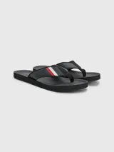 Ojotas negras Tommy Hilfiger con tira ancha de poliuretano acolchada y suela de goma EVA. Detalle de cinta distintiva con los colores de la marca en la tira.