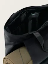 Bolso tote negro multiusos con dos asas, tejido repelente al agua, cierre principal con cremallera, bolsillo exterior con cremallera y compartimento especial para transportar mat.