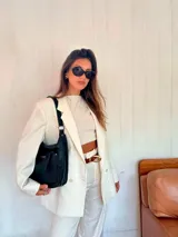 Bandolera negra de cuero sintético con asa de hombro y correa regulable. Cuenta con un bolsillo frontal con cierre y un bolsillo dorsal con cierre.