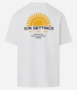 Remera de algodón blanca, corte relajado (relaxed fit), con cuello redondo y manga corta. Presenta un pequeño estampado frontal en el pecho con un sol estilizado y el texto "Sun Settings".
