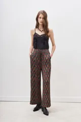 Conjunto de pantalón y kimono con estampado floral en tonos rojos y dorados sobre fondo negro. El pantalón es de corte palazzo y el kimono tiene mangas anchas.
