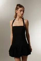 Vestido mini negro sin mangas de algodón, con cuello recto, corte ajustado y falda con volados.