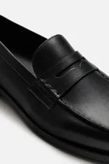 Mocasín de cuero negro con antifaz en el empeine y suela a tono con ligero tacón.