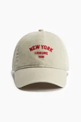Gorra color beige de sarga de algodón con efecto lavado y bordado rojo con la leyenda "New York Leisure 1990".