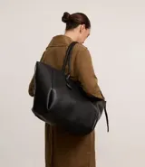 Bolso shopper grande de cuero sintético negro con asas medianas y cierre de cremallera. Incluye un dije colgante en forma de corazón y una pequeña cartera extra.