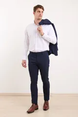 Traje de vestir azul marino, compuesto por saco de dos botones y pantalón de corte slim. Incluye camisa blanca de vestir y zapatos marrones acordonados.