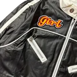 Campera crop negra con detalles en blanco, cierre frontal, cuello mao con doble botón y bolsillos con cierre.