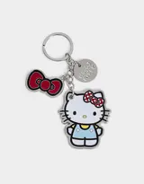 Llavero metálico plateado con dijes esmaltados de Hello Kitty, un moño rojo y un dije circular con el logo de Hello Kitty.