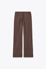 Pantalón marrón de tela fluida, corte recto, tiro medio y cintura elástica ajustable con cordones. Incluye bolsillos laterales ocultos en la costura.