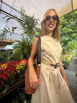 Bandolera pequeña de textura símil cuero color caramelo/marrón, con dos compartimentos principales con cierre. Correa ancha ajustable de tela negra con inscripción en relieve.