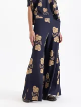 Pantalón de tejido de punto acanalado color azul marino con estampado de cerezas en tono beige. Presenta cintura elastizada y piernas amplias.