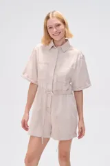 Mono corto blanco de algodón, con cuello camisero, cierre frontal con botones, mangas cortas y bolsillos.