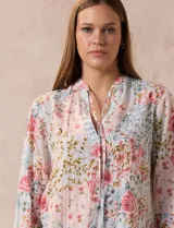 Blusa de gasa plisada estampada con flores azules, marca Floral & Ivy. Cuello a la base, escote en V y lazo de ajuste.