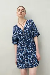 Vestido corto color marrón con estampado de hojas blancas, escote en V, mangas cortas y cintura marcada.