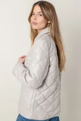 Campera de cuero negra con diseño matelassé de rombos, cuello camisero, cierre frontal con botones a presión, dos bolsillos delanteros y puños con botón.