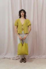 Blusa blanca de lino con escote en V, mangas cortas abullonadas y cierre frontal con lazos.