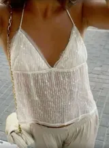 Top blanco con lentejuelas, breteles finos y escote en V.