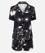 Conjunto de pijama de dos piezas confeccionado en viscolycra, compuesto por una blusa de manga corta con cuello solapa y botones frontales, y un short con cintura elástica y lazo. Estampado integral de temática espacial con estrellas, planetas y explosiones en tonos rosados y blancos sobre fondo negro.