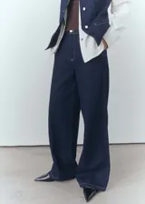 Pantalón de jean wideleg azul oscuro, de tiro medio, con cinco bolsillos y cierre frontal con cremallera y botón.