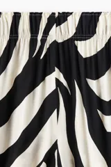 Pantalón tobillero de viscosa con estampado abstracto en blanco y negro, tiro alto con elástico en la cintura, bolsillos laterales y piernas amplias rectas.