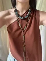 Collar corto con cuentas grandes de madera color marrón oscuro, separadores de metal con incrustaciones de turquesas y cuentas pequeñas turquesas. Cierre con cadena de acero quirúrgico y ganchito para regular el largo.