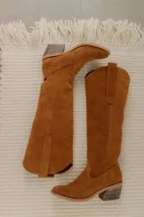 Bota alta de cuero color beige, estilo texana, con caña alta y taco bajo.