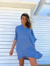 Túnica celeste de lino rústico, corte holgado, cuello en V con botones y ruedo irregular con flecos.