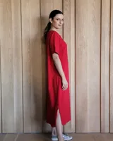 Vestido midi negro con cuello redondo y mangas cortas. Presenta dos bolsillos cuadrados en el pecho y ribetes blancos en cuello, mangas, bolsillos y ruedo.