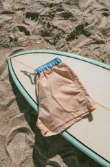 Short de baño color durazno con cintura elástica celeste y cordón ajustable blanco.