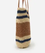 Bolso tipo tote de paja tejida con diseño de rayas horizontales en color natural, marrón y azul marino. Posee asas de hombro en cuero sintético color camel y un dije metálico circular en el frente.
