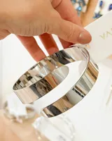 Brazalete rígido plateado con forma de espiral.