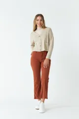 Cardigan tejido color beige con escote en V, cierre con botones, bolsillos delanteros y logo en grifa de cuero.