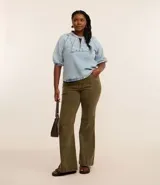 Pantalón flare de sarga color verde oliva, con cintura ancha, doble botón, cierre tradicional, trabillas, detalle de recortes y bolsillos.