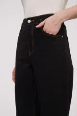Pantalón negro de corte recto con costuras en color ocre y ruedo con dobladillo ancho.