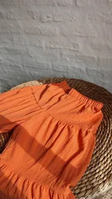 Pantalón palazzo naranja con elástico en la cintura y diseño escalonado con volados.