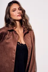 Camisa color marrón de gamuza sintética, de corte recto, con cuello clásico, cierre frontal con botones y mangas largas.