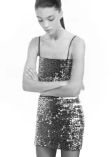Conjunto de top corto y falda mini con lentejuelas plateadas. El top es de tirantes finos y la falda es ajustada.