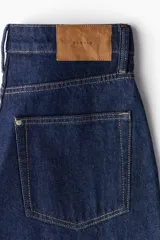Pantalón de jean azul oscuro de corte holgado, con tiro alto, cinco bolsillos y cierre con botón.