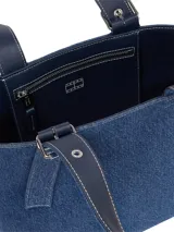 Cartera tipo tote confeccionada en tejido denim azul de Tommy Jeans. Presenta asas de hombro ajustables con hebillas metálicas y ojalillos, un compartimento principal y el logo de la bandera de Tommy Jeans en una placa metálica frontal.