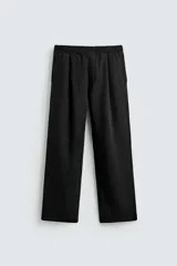 Pantalón negro de corte relajado con cintura elástica ajustable y pliegues en la parte delantera. Presenta bolsillos laterales y bolsillos traseros de parche.